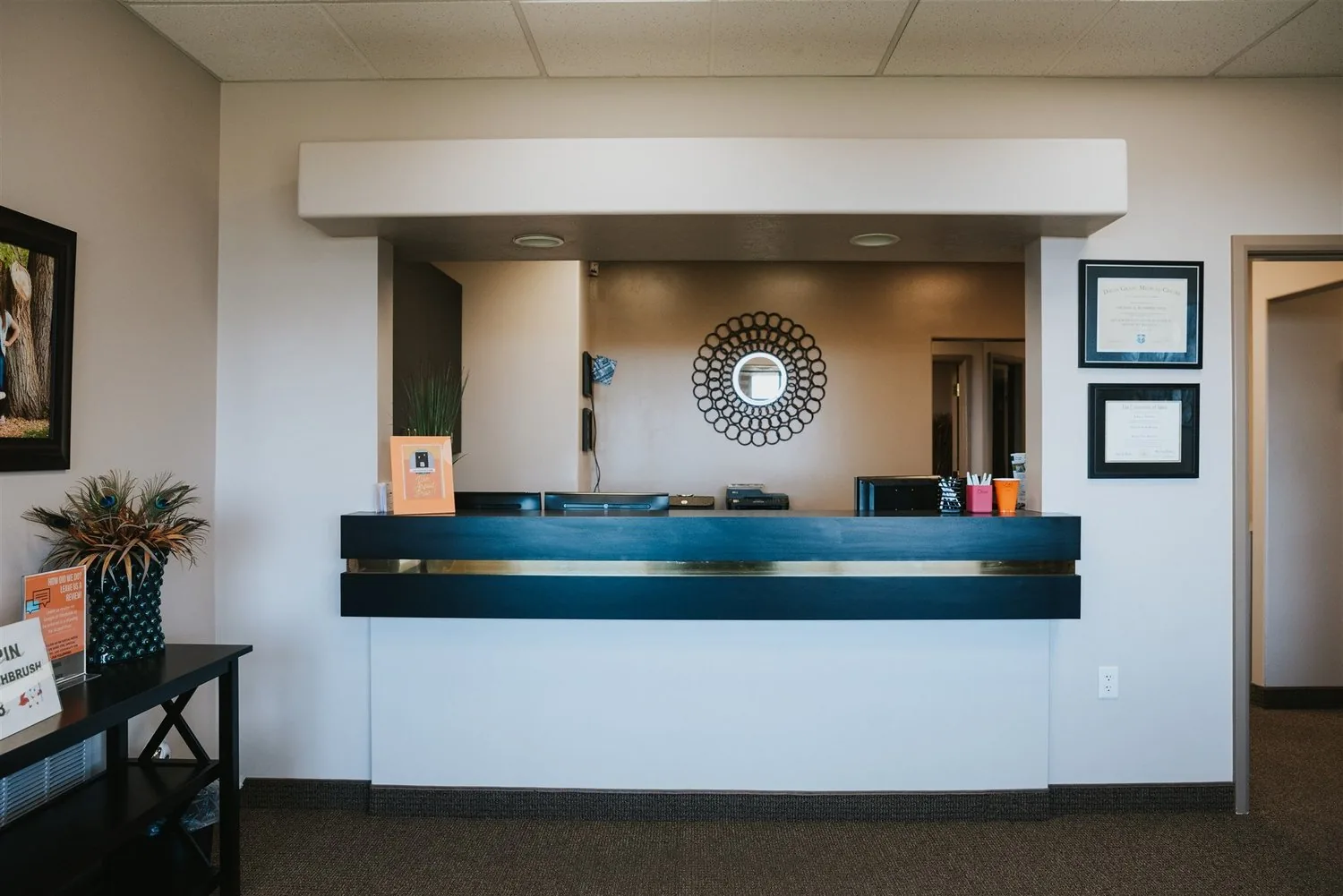 Reception check-in desk at a dental office with a decorative wall mirror in the background.